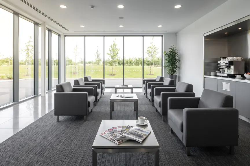 A bright customer waiting room with grey armchairs on clean charcoal carpet.